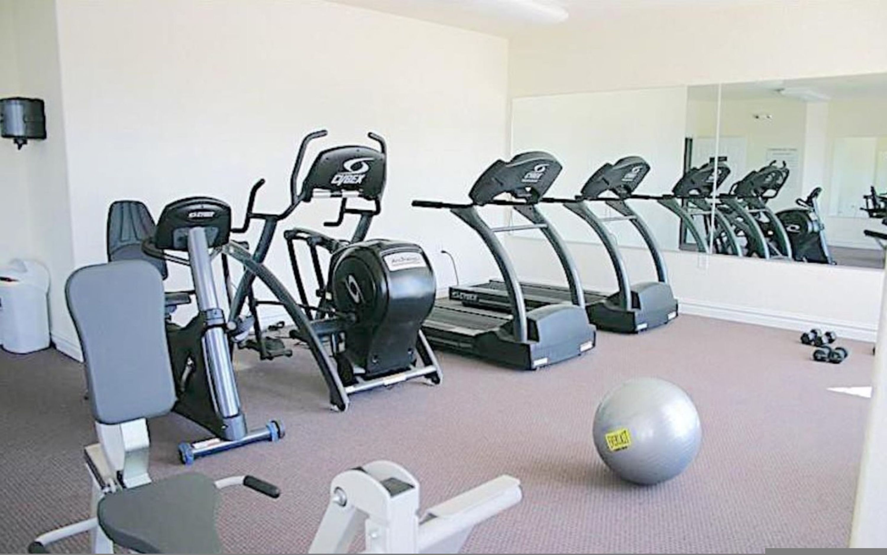 Een fitnessruimte met loopbanden, elliptische trainers en losse gewichten.