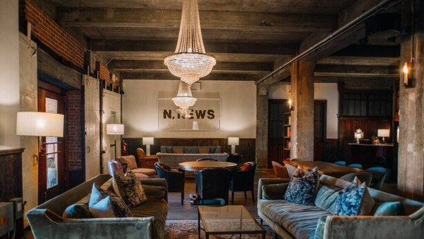 A spacious lounge area with a chandelier, sofas, and a round table. - Ice Ice Baby Downtown Newport News (Newport News)