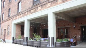 A building with a brick facade, large windows, and a covered entrance area with planters. - Ice Ice Baby Downtown Newport News (Newport News)