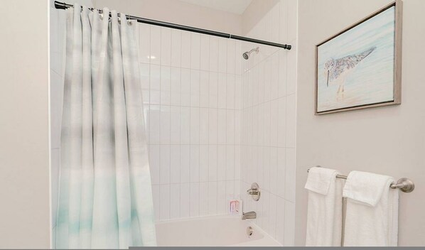 Un baño con cortina de ducha, un cuadro en la pared y un perchero.