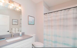 A bathroom with a sink, toilet, and shower curtain. - Ice Ice Baby Downtown Newport News (Newport News)