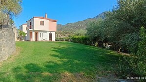 A two-story house with a red roof, a stone wall on the left, and a well-maintained lawn. - Evinos Village Resort (Nafpaktos)