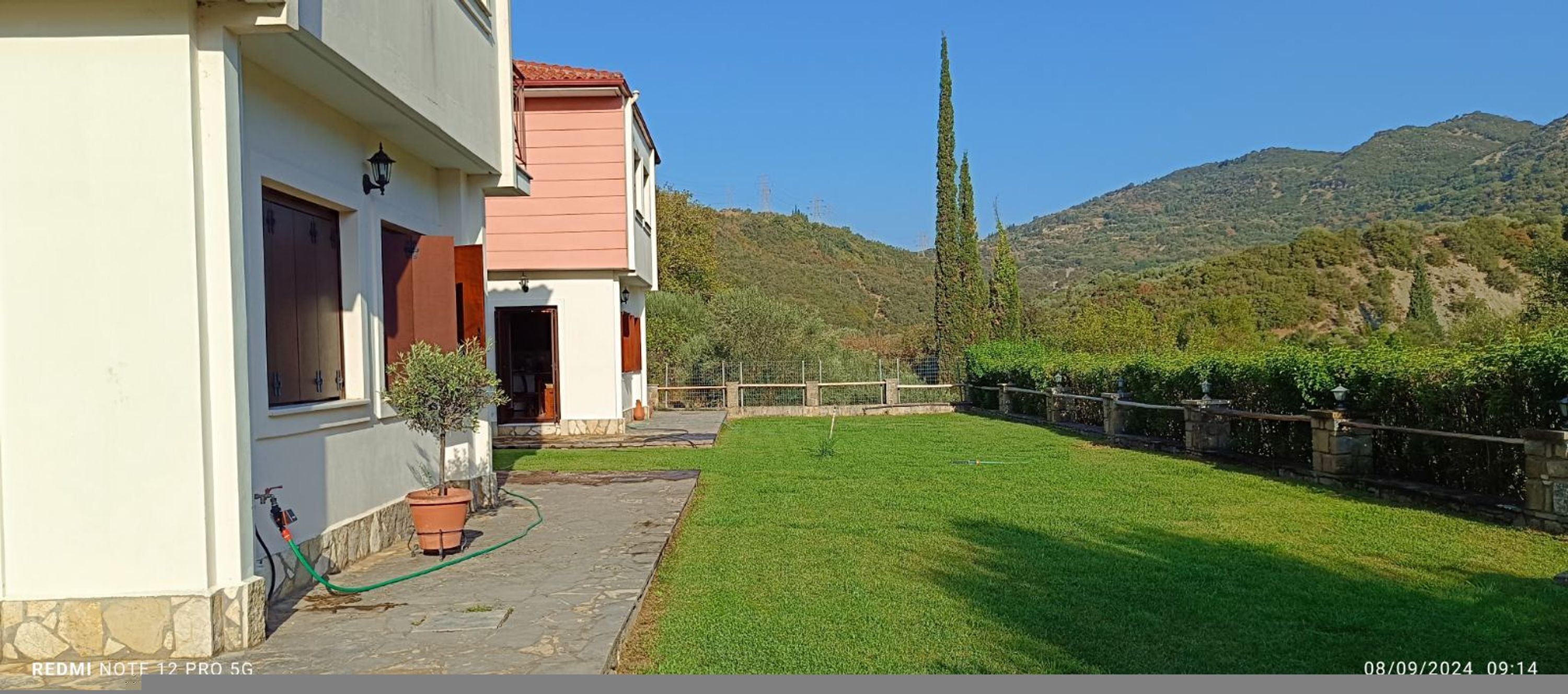 A house with a paved patio, a small lawn, and a stone wall.