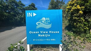 A sign for Ocean View House Nakijin with a coastal scene illustration. - Ocean View House Nakijin (Nakijin)