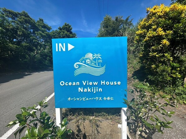 Find your way to the Ocean View House Nakijin, marked by a distinctive sign with a house on a wave graphic.