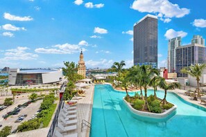A swimming pool with palm trees, a modern building, and a historic tower. - Designer Studio | Free Parking | Bay Views (Miami)
