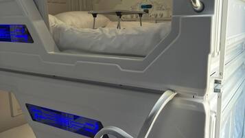 A futuristic interior with a bunk bed, a control panel, and a circular window.