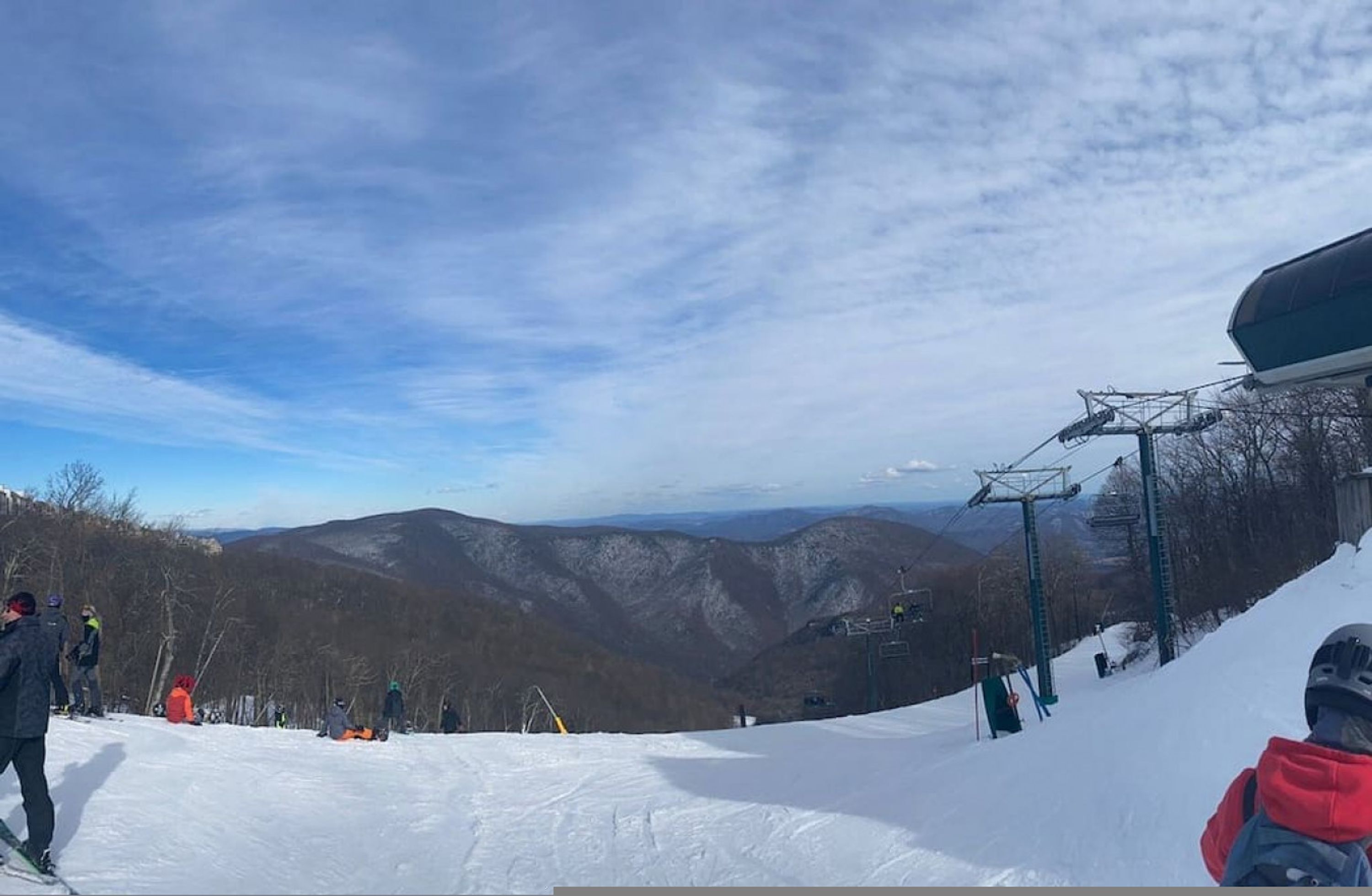 Pista da sci con vista panoramica sulle montagne circostanti e una seggiovia sullo sfondo.