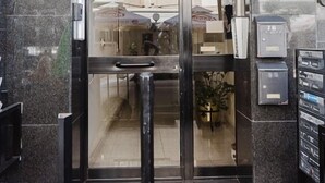 L’entrée d’un hôtel, avec une porte en verre, un comptoir d’accueil et une boîte aux lettres.
