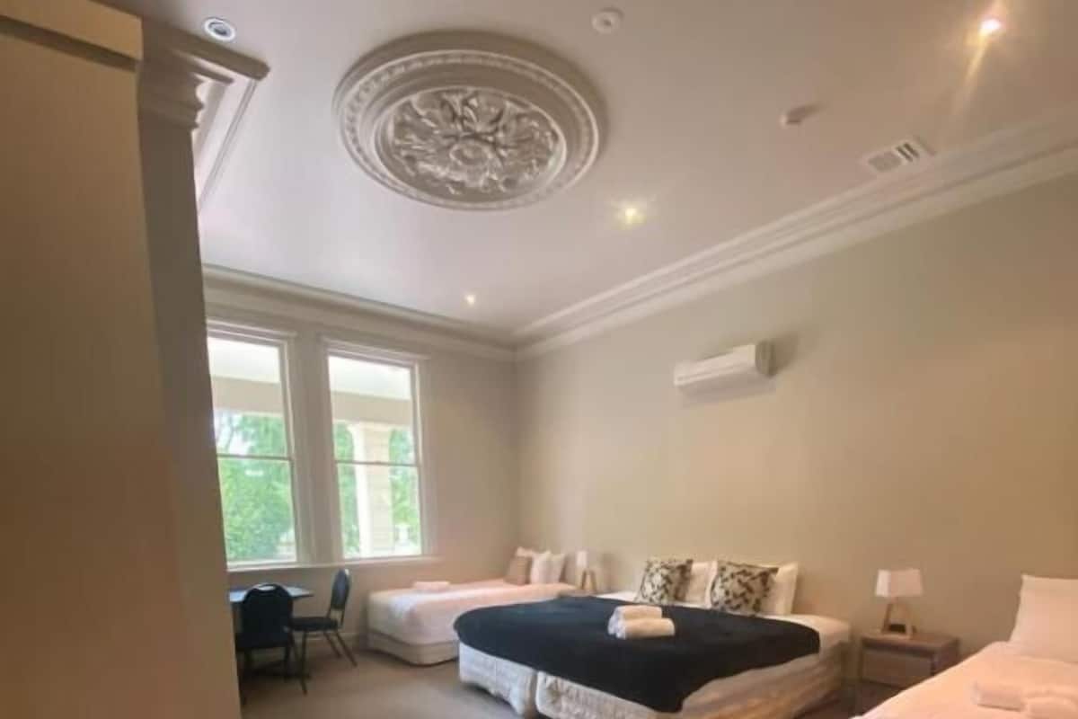 A bedroom with two beds, a desk, and a chair.