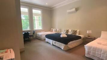 A bedroom with two beds, a desk, and a chair.