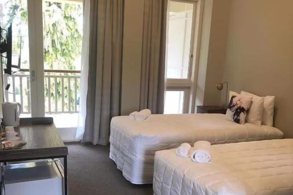 A hotel room with two beds, a desk, and a chair.