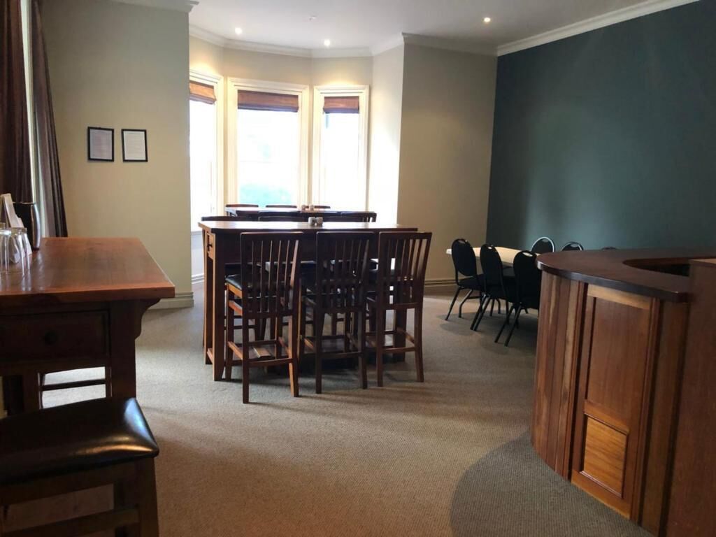 Un comedor con mesa y sillas de madera, una zona de bar con mostrador, y vistas al exterior a través de amplios ventanales.