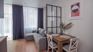 A modern living room with a sofa, a dining table with chairs, and a large window with curtains. - Contactless check-in, functional area of ​​the apartment, workplace (Lviv)