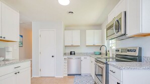 Una cocina moderna con armarios blancos, lavavajillas, estufa y microondas.