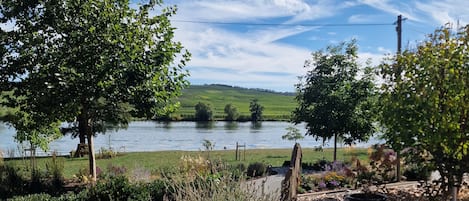 A lakeside view with a wooden deck, a stone pathway, and a view of the lake and hills.