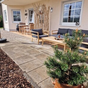 Eine Terrasse mit Gartenmöbeln, einem Holztisch und einem Blumentopf.