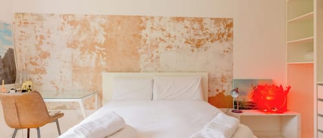 Hotellihuone, jossa on suuri sänky, työpöytä, tuoli, yöpöytä lampun kanssa ja vaatekaappi.