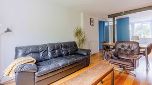 Un salon avec un canapé en cuir noir, un fauteuil en cuir marron, une table basse en bois et une plante en pot.