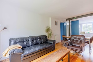 A living room with a black leather sofa, a brown leather armchair, a wooden coffee table, and a potted plant. - 1BD Loft Style Flat in the Heart of Islington (Greater London)
