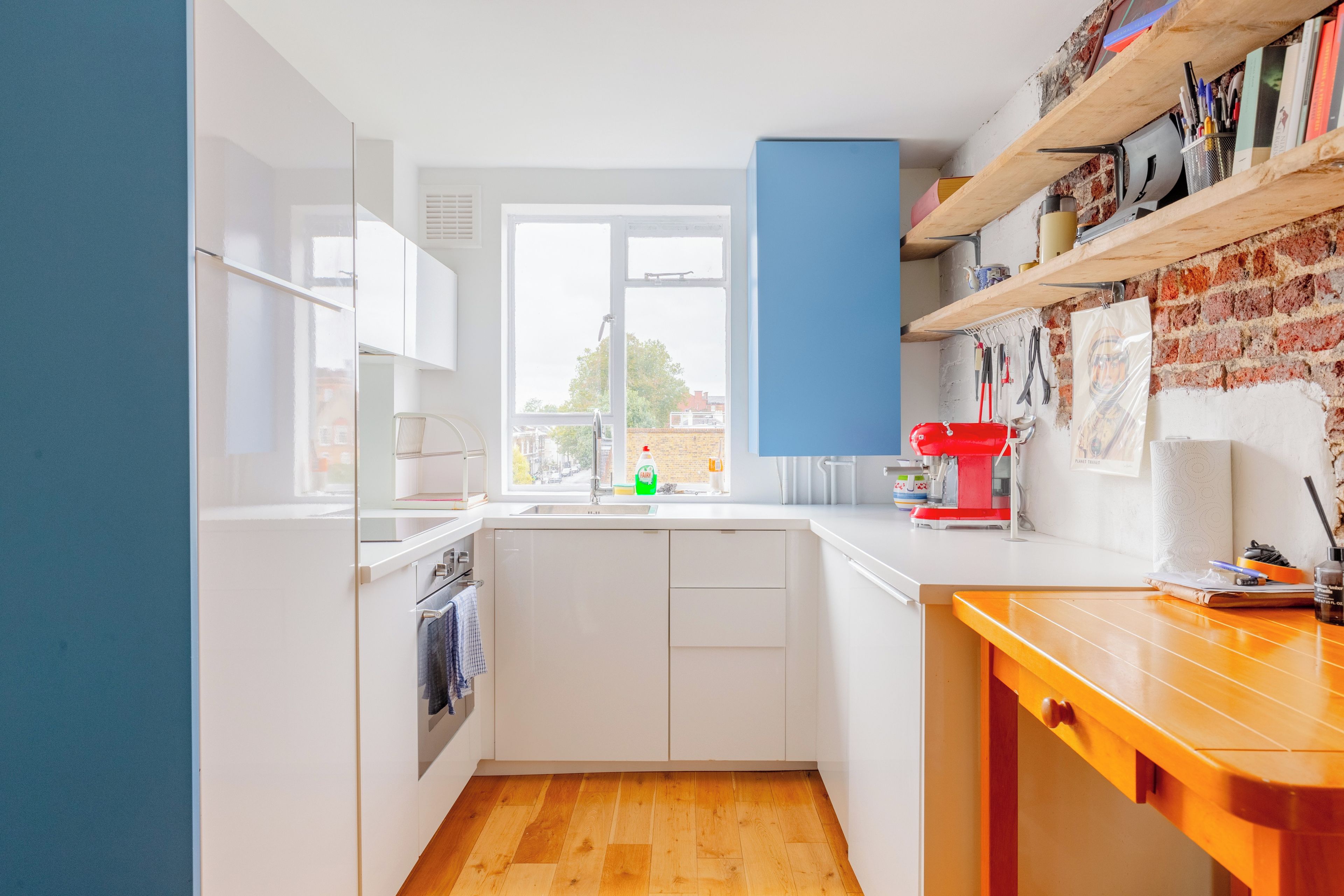 A compact kitchen with white cabinets, a wooden countertop, and a view through the window.