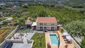 Ein zweistöckiges Haus mit Swimmingpool, Sitzgelegenheiten im Freien und einem Garten.