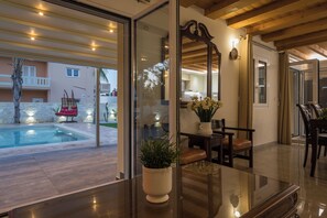 Un interior moderno con un separador de vidrio, una piscina y mobiliario de exterior.