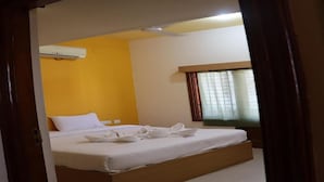 Een hotelkamer met een bed, een raam met gordijnen en een airconditioning op de muur.