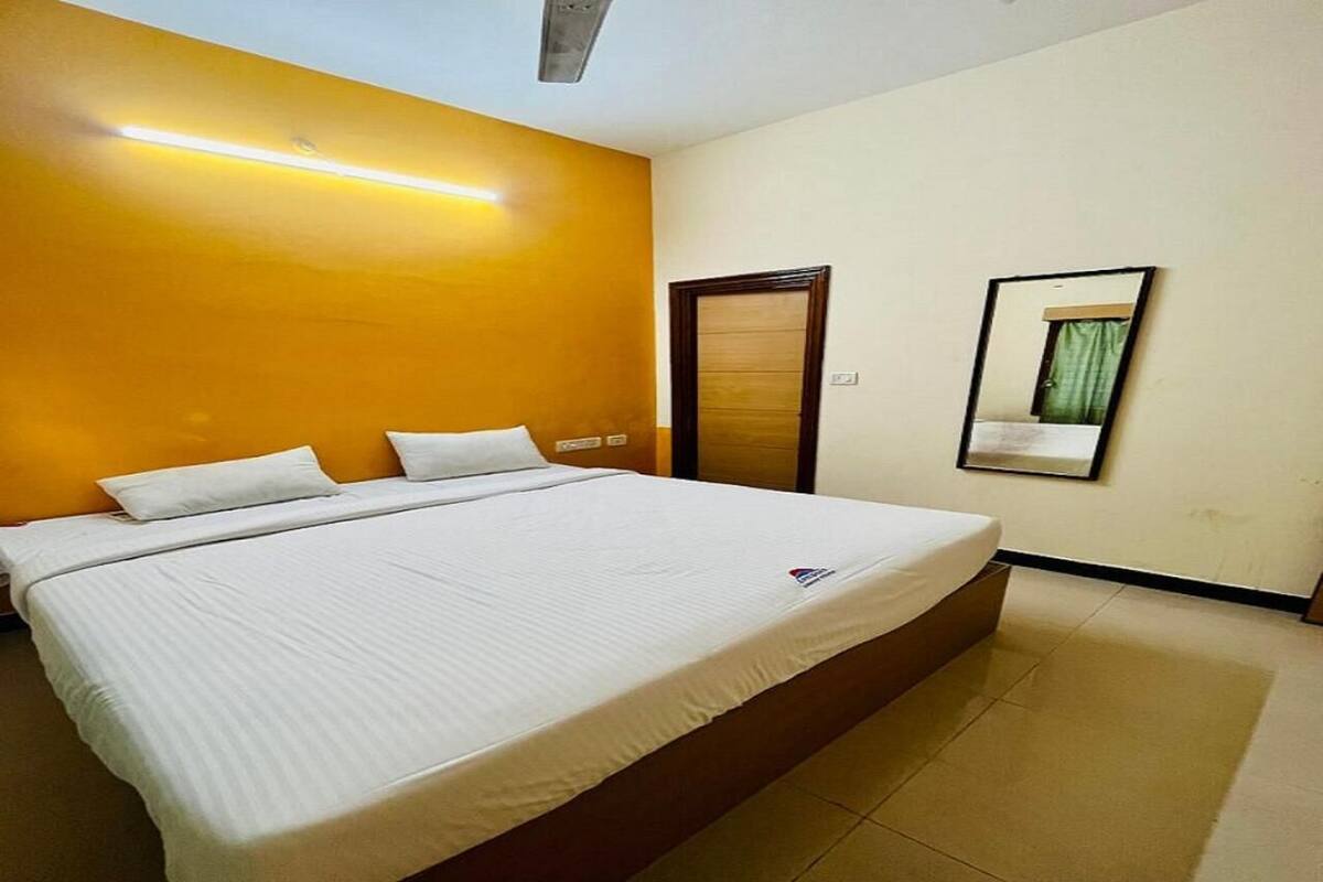 A hotel room with a large bed, a wooden door, and a mirror on the wall.