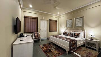 Un dormitorio con cama, mesitas de noche, escritorio, silla y televisor.