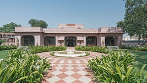 A building with a central fountain, surrounded by a checkered pathway and lush greenery. - Raj Niwas Palace (Dhaulpur)