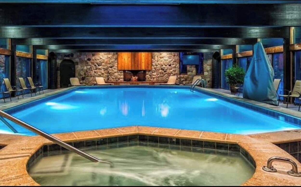 Une grande piscine intérieure avec un mur en pierre et des armoires en bois en arrière-plan.