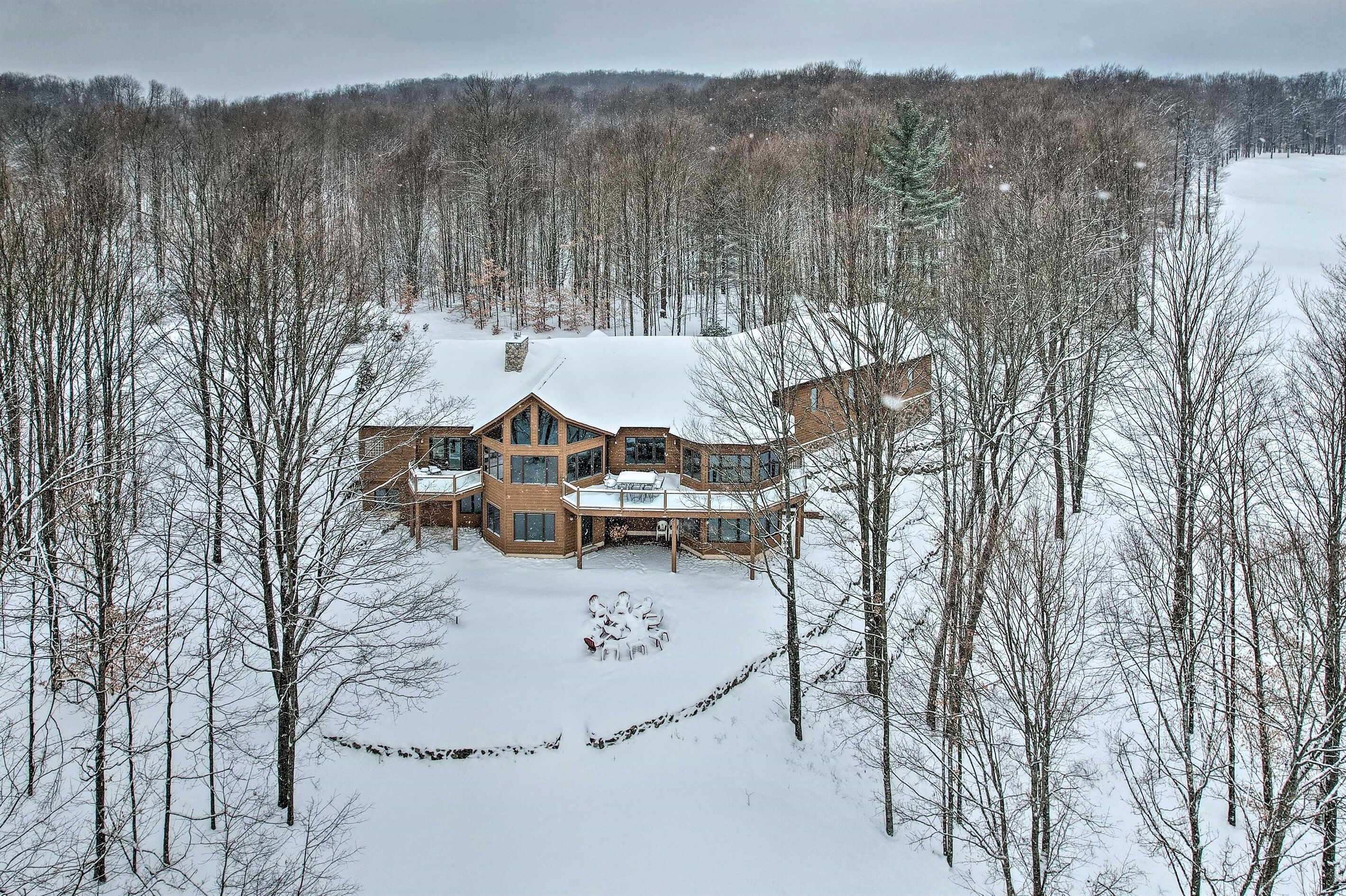 Une grande maison en bois à plusieurs étages, entourée d’une forêt enneigée.