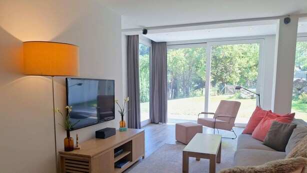Una sala de estar moderna con un televisor de pantalla plana, un sofá, una mesa de centro y un mueble de televisión con objetos decorativos.