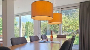 Un comedor moderno con una gran mesa de madera, seis sillas y dos lámparas colgantes.
