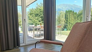 Una habitación con un amplio ventanal corredera que da a un espacio exterior con una mesa y sillas.