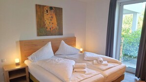 Una cama doble con ropa de cama blanca, un cabecero de madera, mesitas de noche con lámparas y un cuadro sobre la cama.