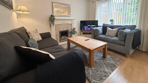 Un salon avec une cheminée, deux canapés, une table basse et un téléviseur.