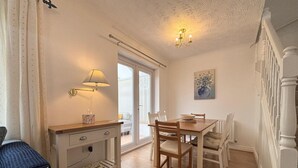 Un coin repas avec une table et des chaises en bois, une lampe et un tableau au mur.