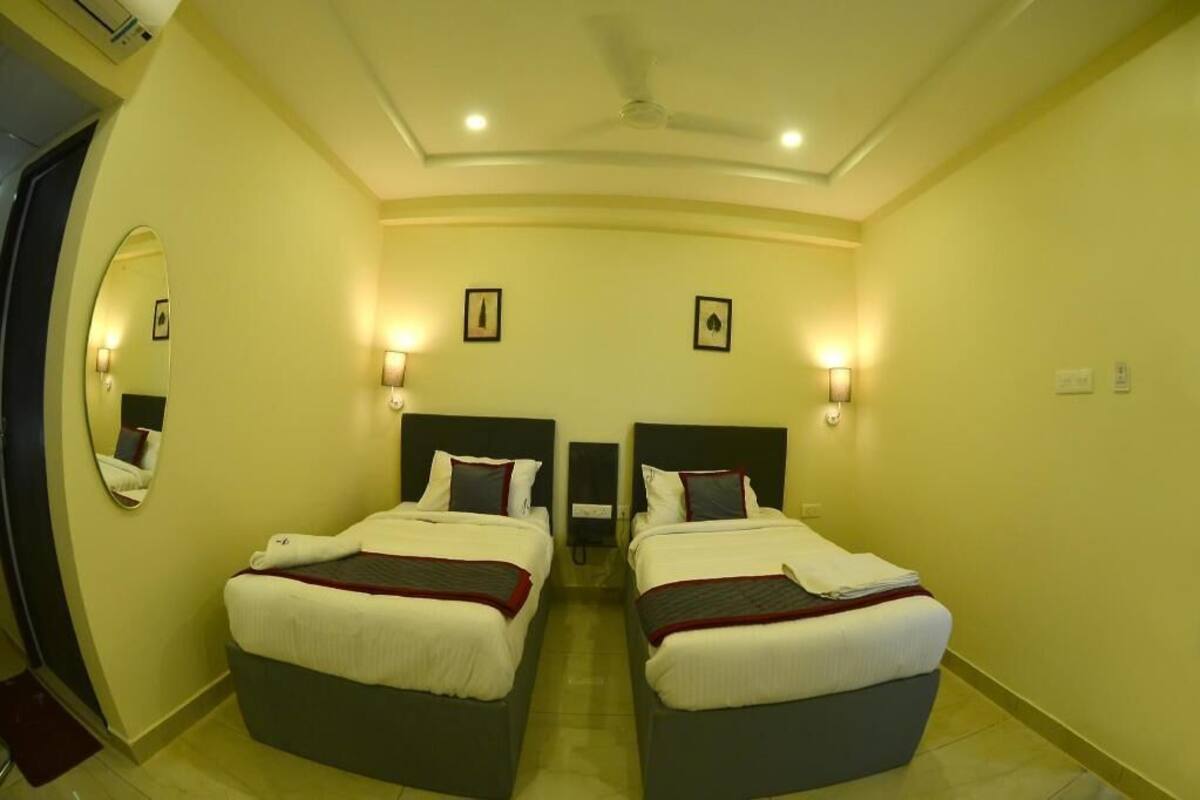 A hotel room with two beds, a ceiling fan, wall-mounted lights, and a mirror.