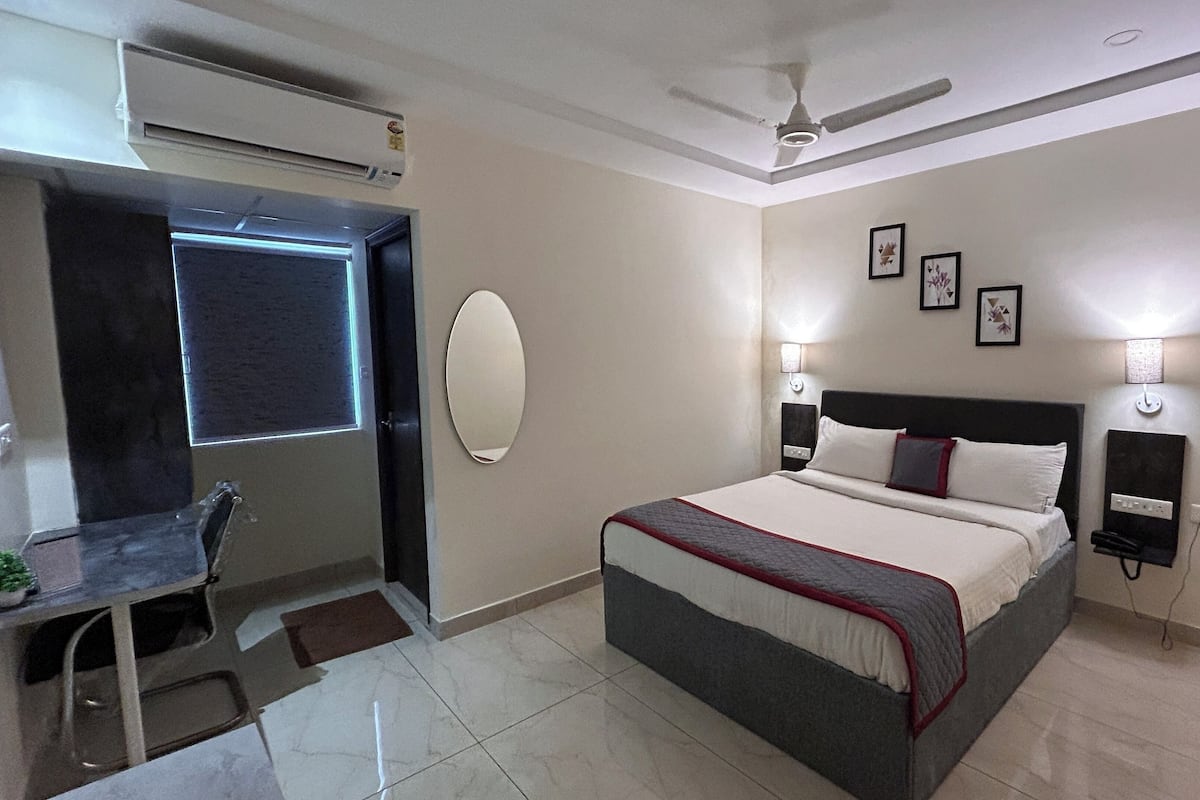 A hotel room with a bed, bedside tables, a desk, and a ceiling fan.