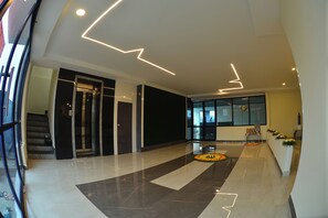 Egy modern előtér márványburkolattal, lépcsővel és egy virágdíszítéssel ellátott recepciós területtel.
