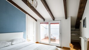 A bedroom with a bed, a wooden bench, a radiator, and a sliding glass door leading to an outdoor area.