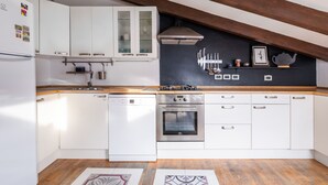 A modern kitchen with white cabinets, a built-in oven, and a wooden countertop.