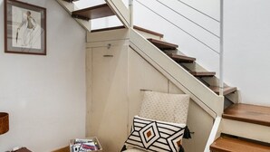 A staircase with wooden steps and white railings, a chair with patterned cushions, and a suitcase on the floor.