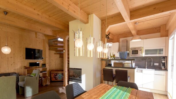 Un accogliente interno in legno con zona pranzo, cucina e soggiorno.