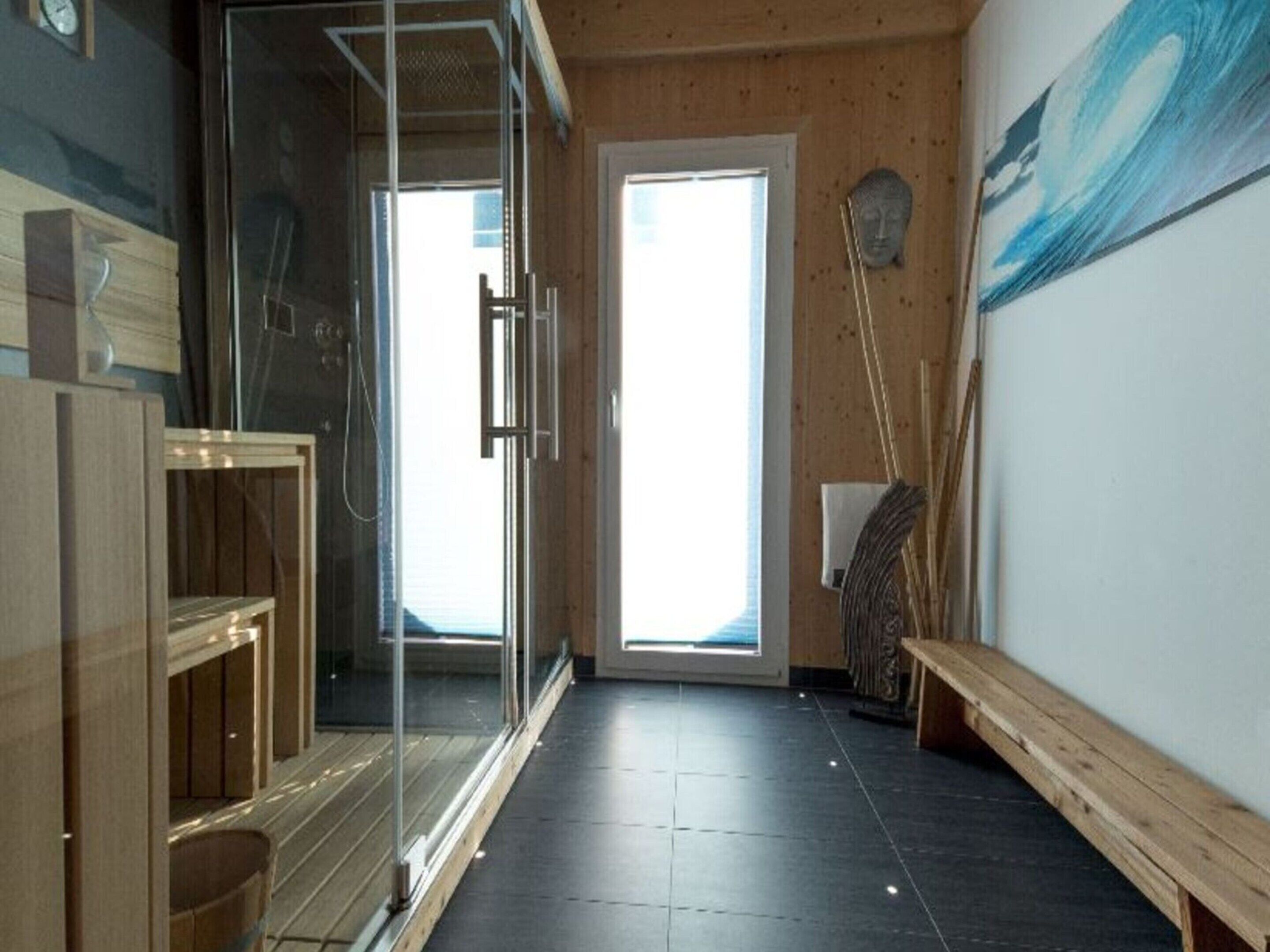 Ein modernes Badezimmer mit Duschabtrennung aus Glas, Holzschränken und einer Sitzbank.