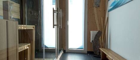 Ein modernes Badezimmer mit Duschabtrennung aus Glas, Holzschränken und einer Sitzbank.