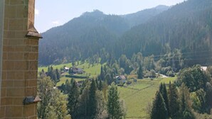 A view of a rural landscape with a brick building in the foreground and a valley with scattered houses and trees.