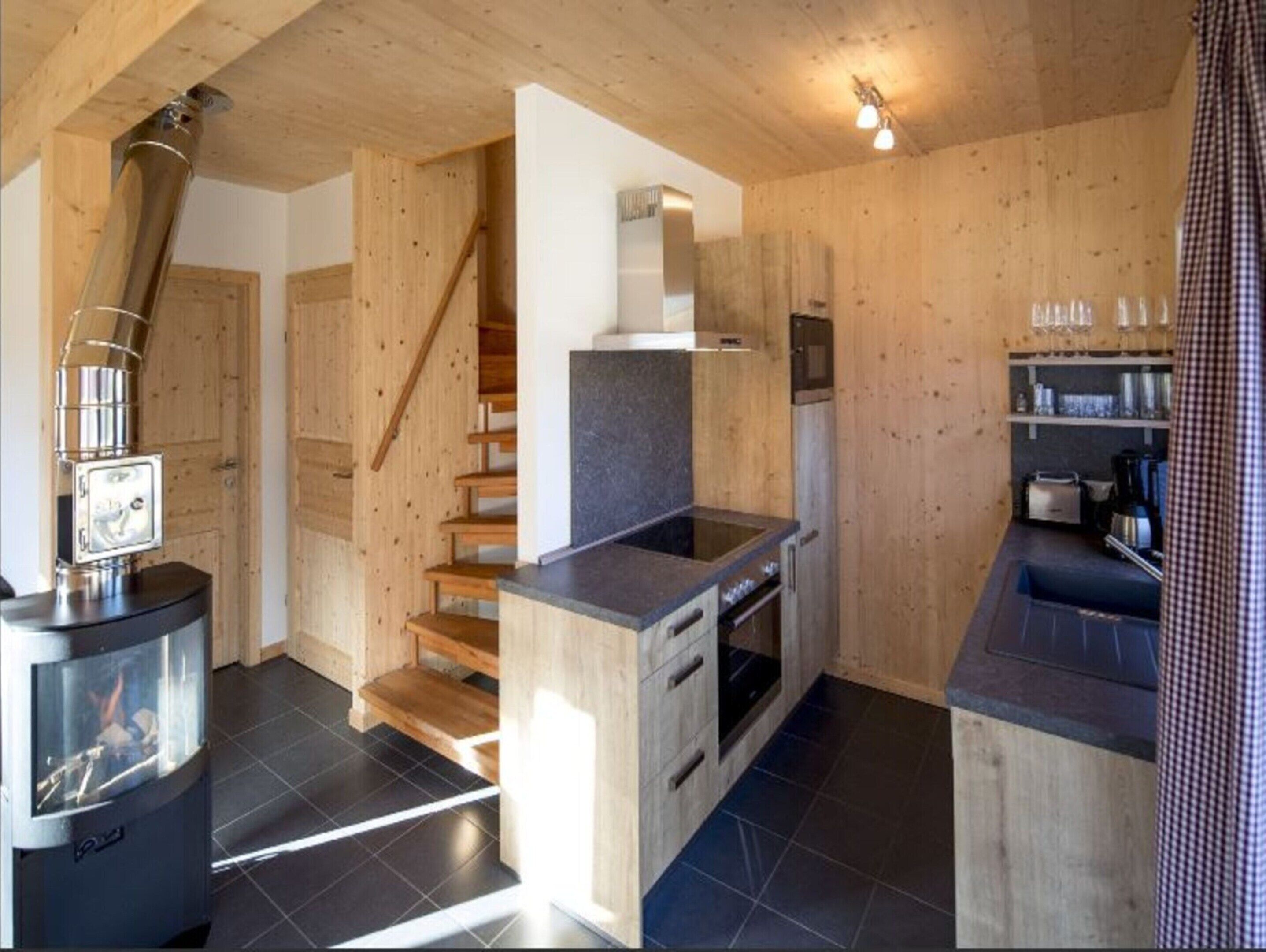 Una cocina moderna con paredes de madera, estufa integrada y un pequeño comedor.
